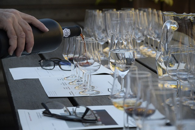 A table with many porto glasses and port being poured for tasting class