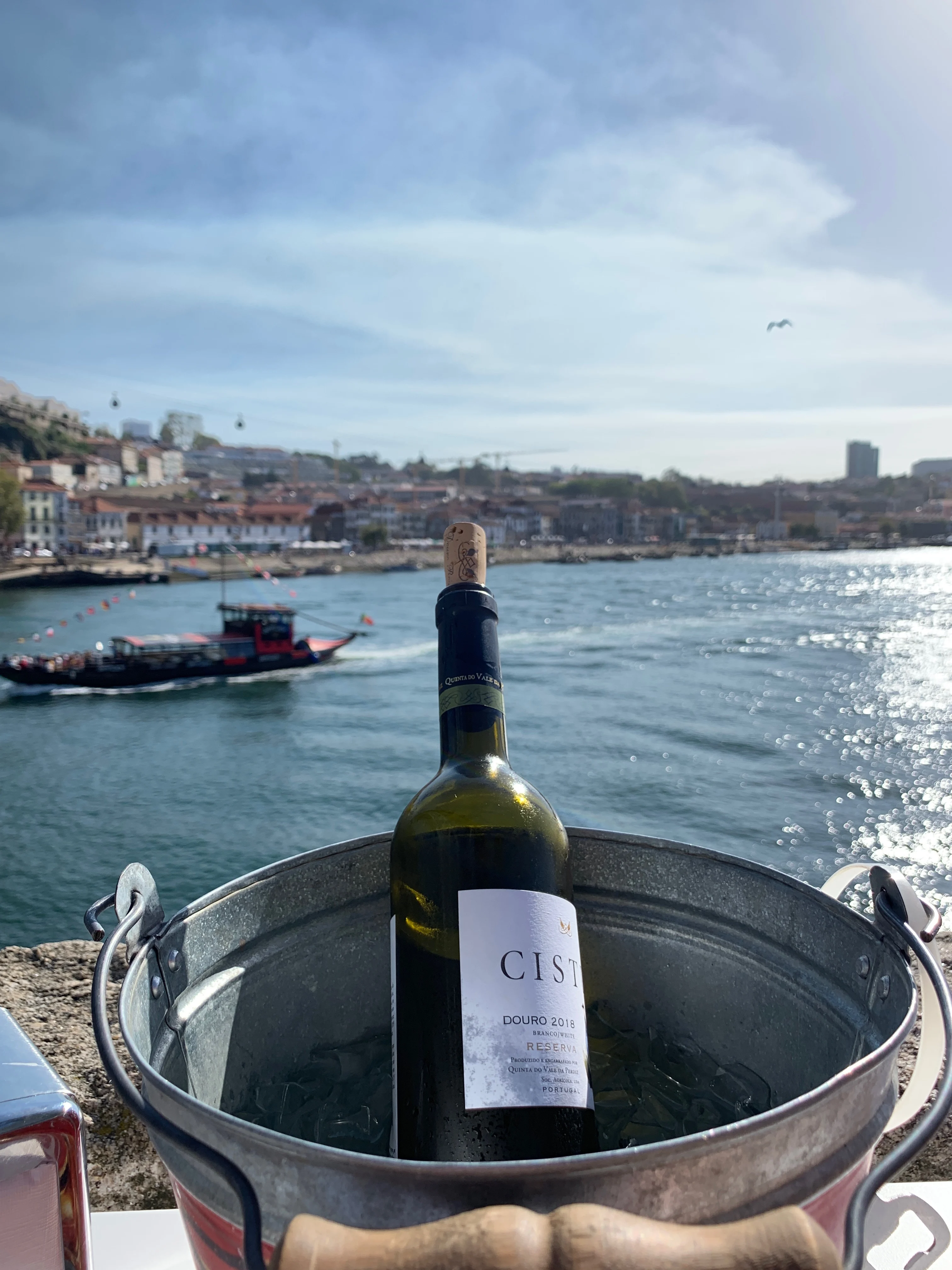 A bottle of wine with a boat on the Douro river floating past in the background