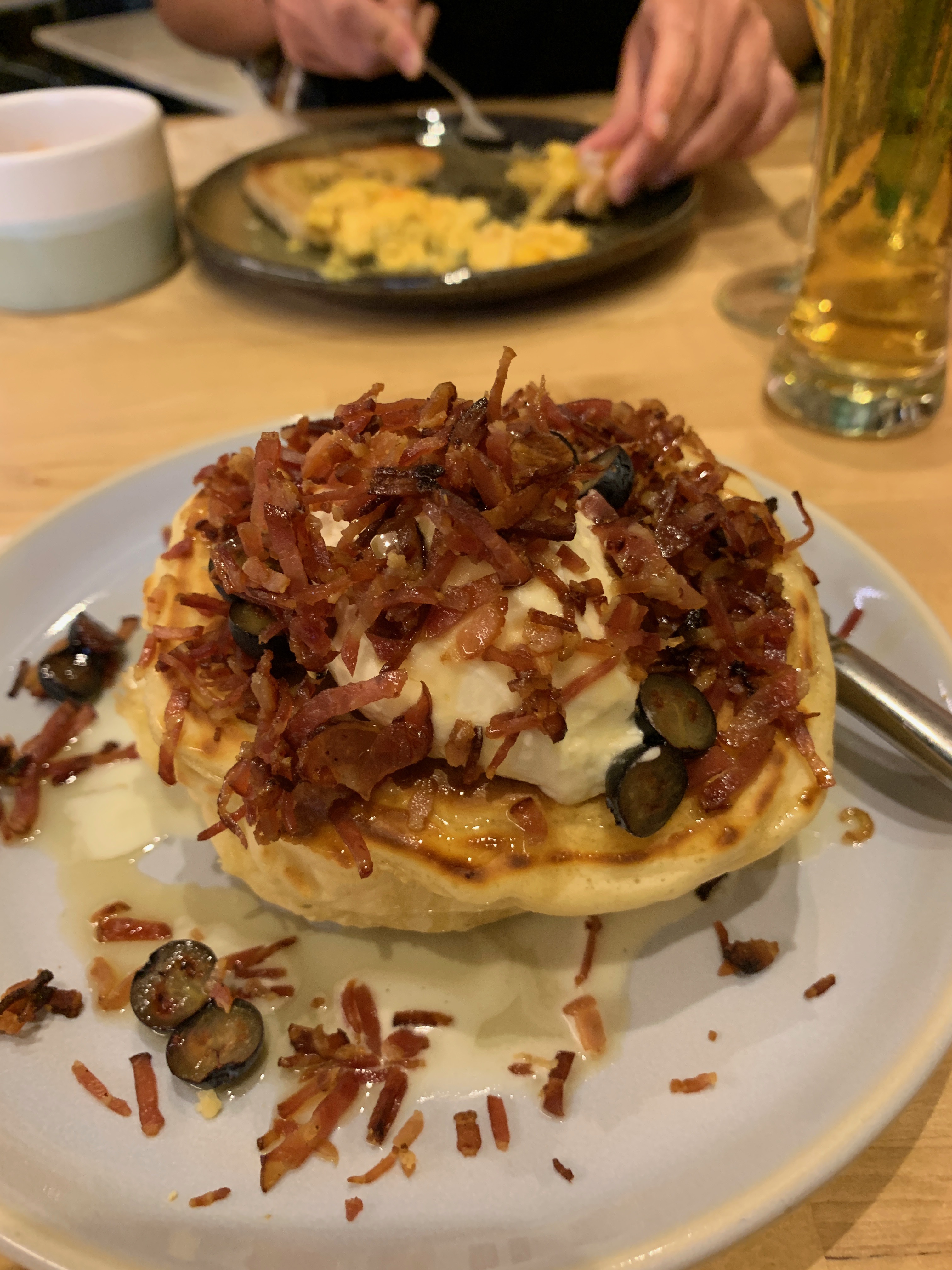 A stack of bacon and grape pancakes topped with fresh cream from Miss Pavlova