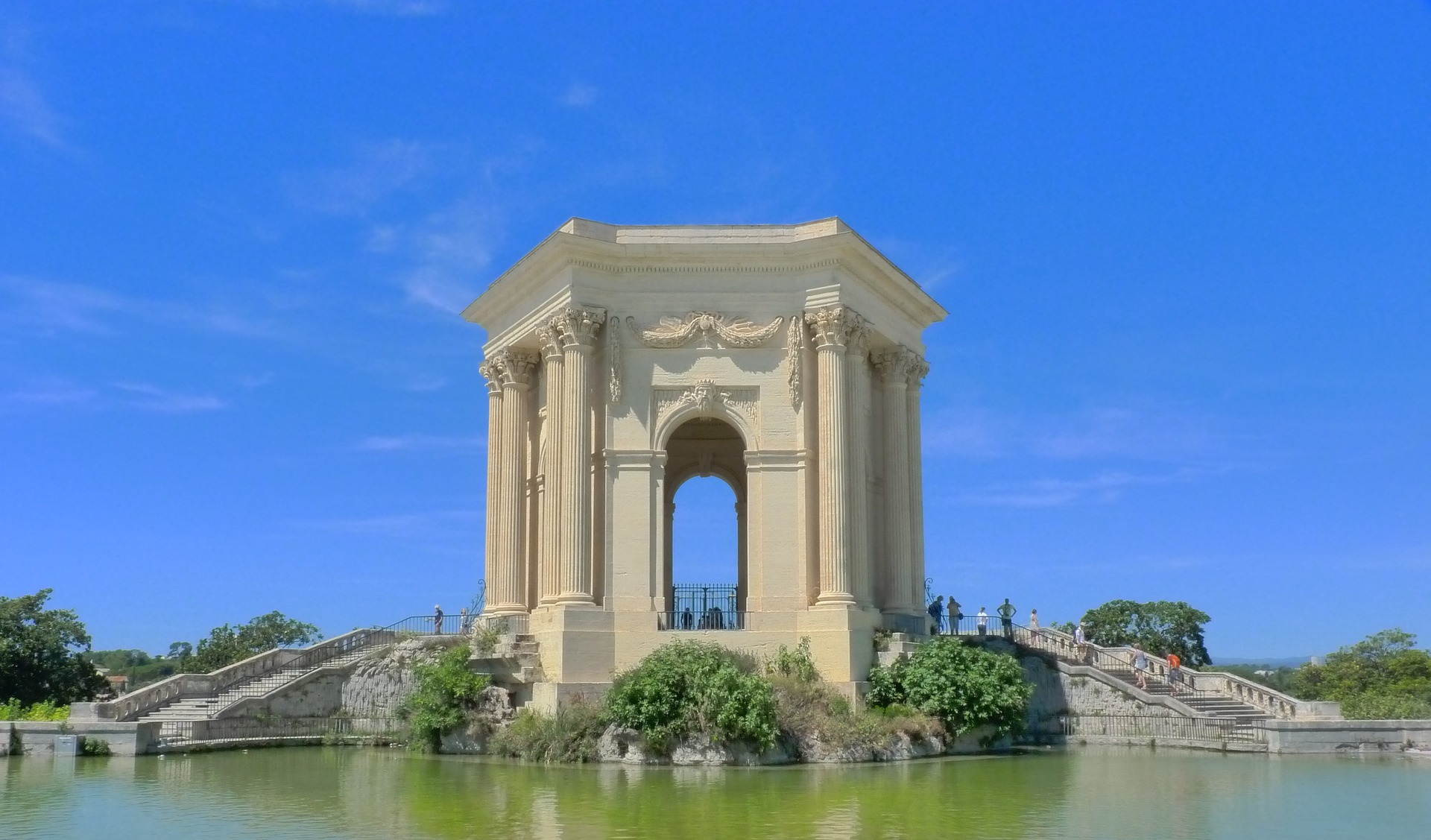 A big, arched structure over a small pond at a park in Montpellier