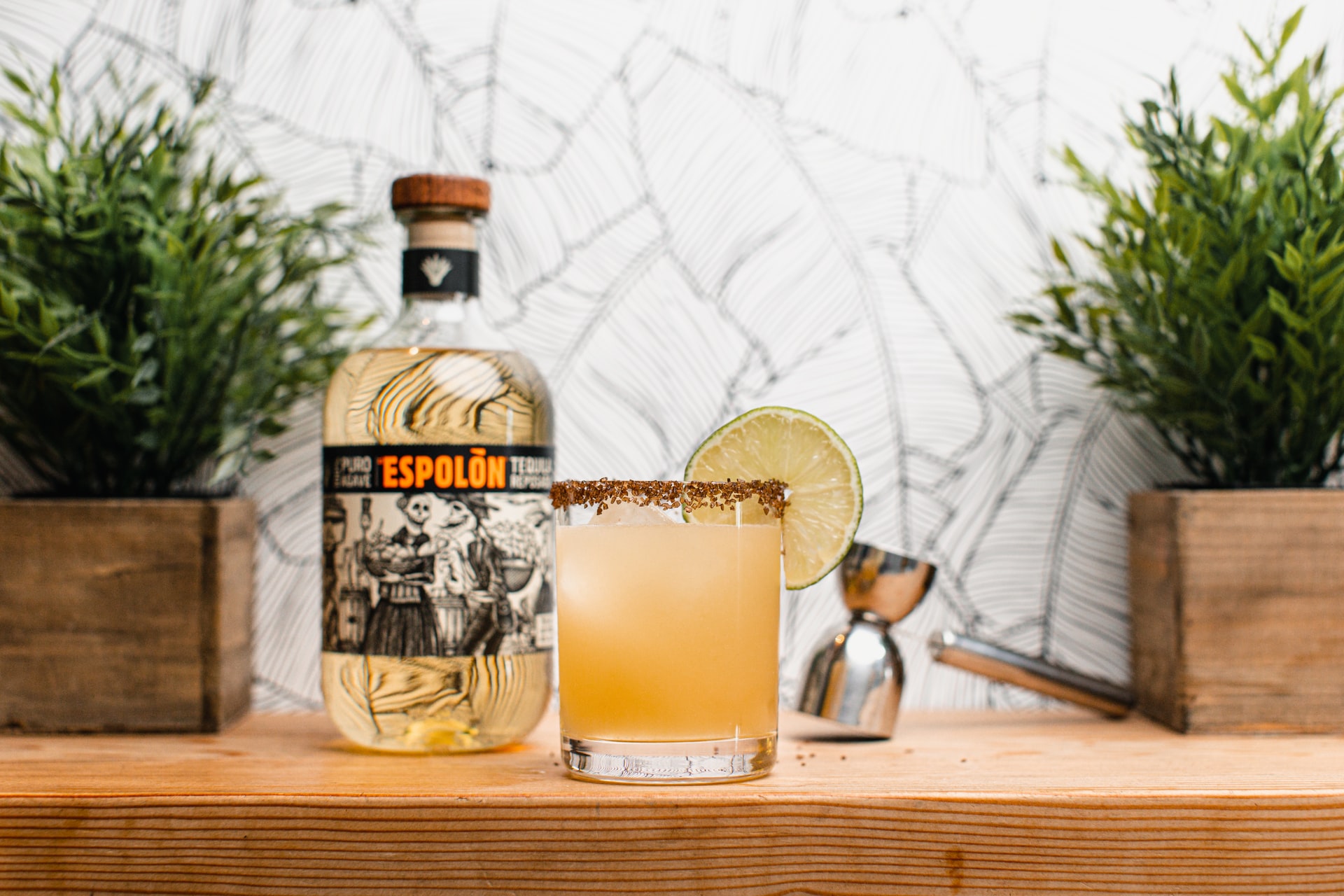 A Paloma with a lime wheel garnish sits on a table next to a bottle of Espolõn tequila.