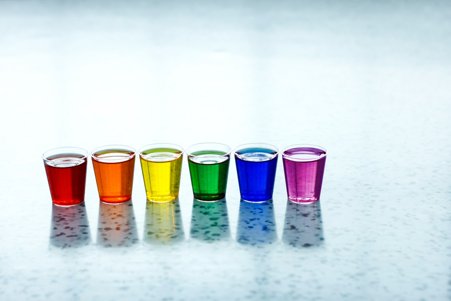 Rainbow colored vodka jello shots lined up in a row.