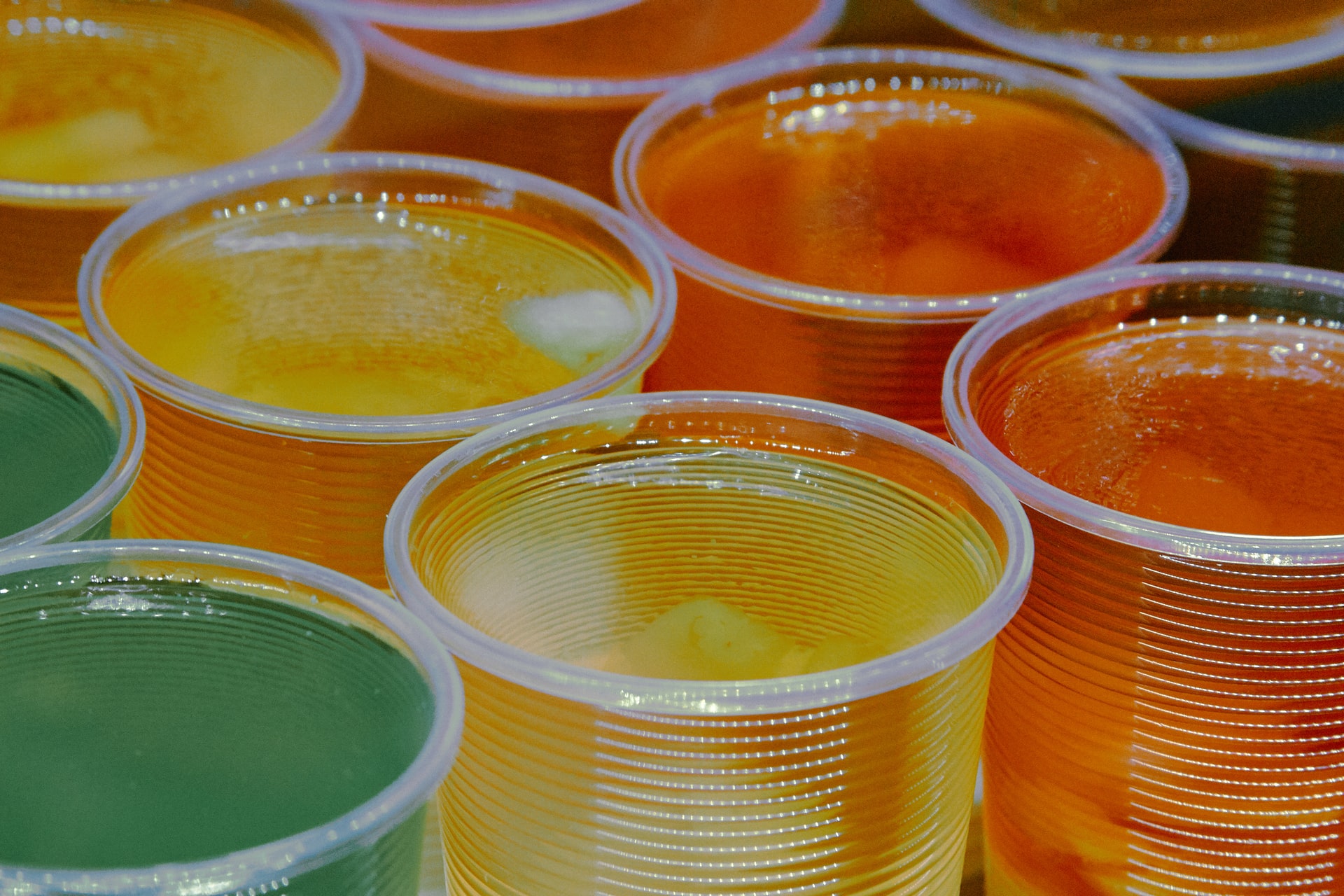 Green, yellow, and orange vodka jello shots lined up next to each other.