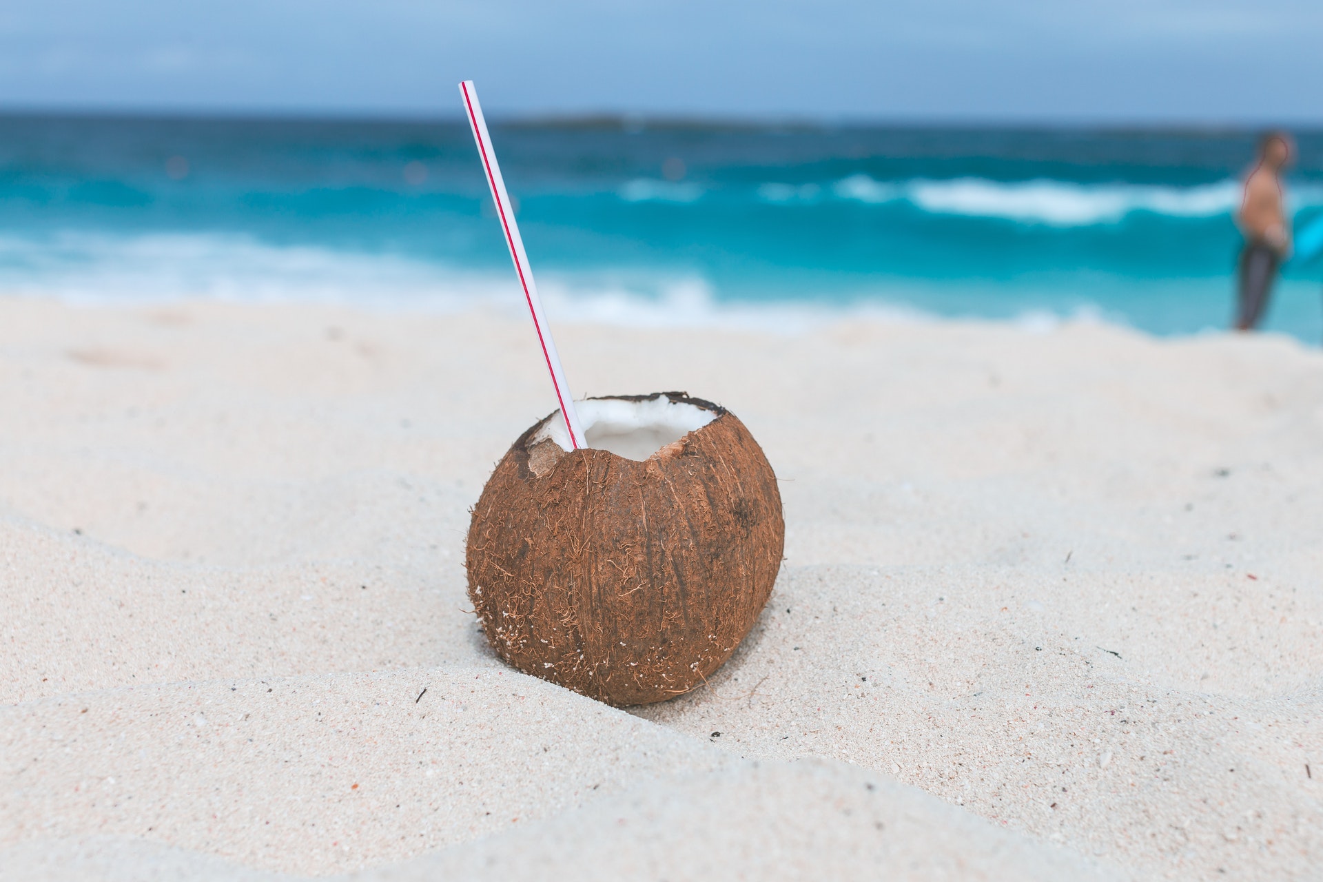 A coconut rum drink inside of a hollowed out coconut on the beach