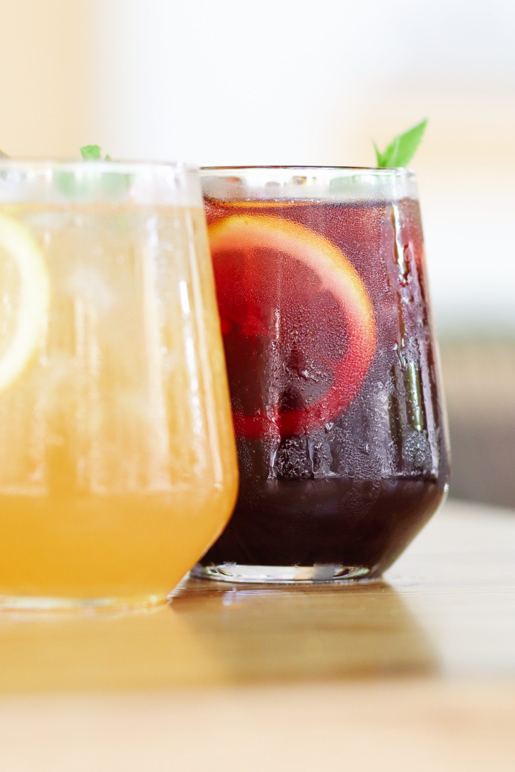 A close up of a bourbon lemonade and a bourbon sweet tea in glasses on a table.