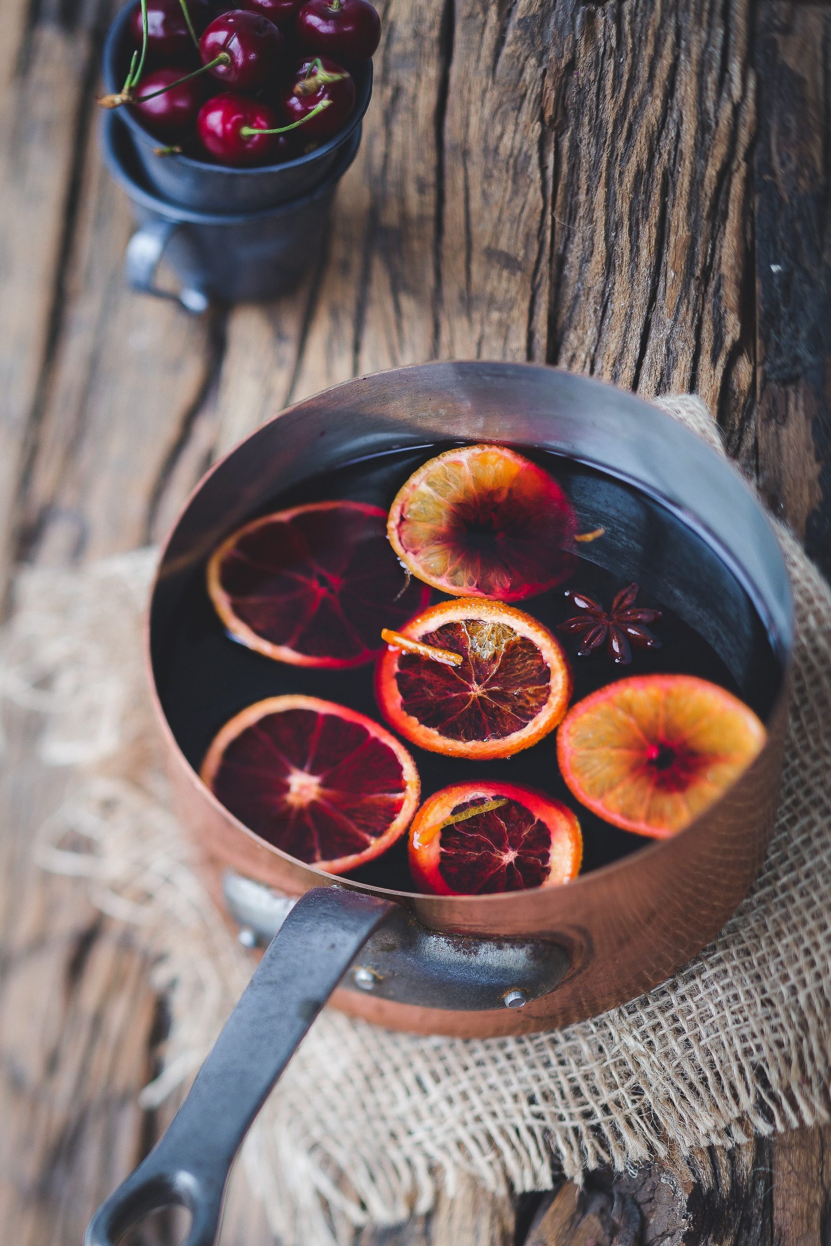 A pot of hot German non-alcoholic Christmas Punch (Kinderpunsch) with oranges and cinnamon sticks.