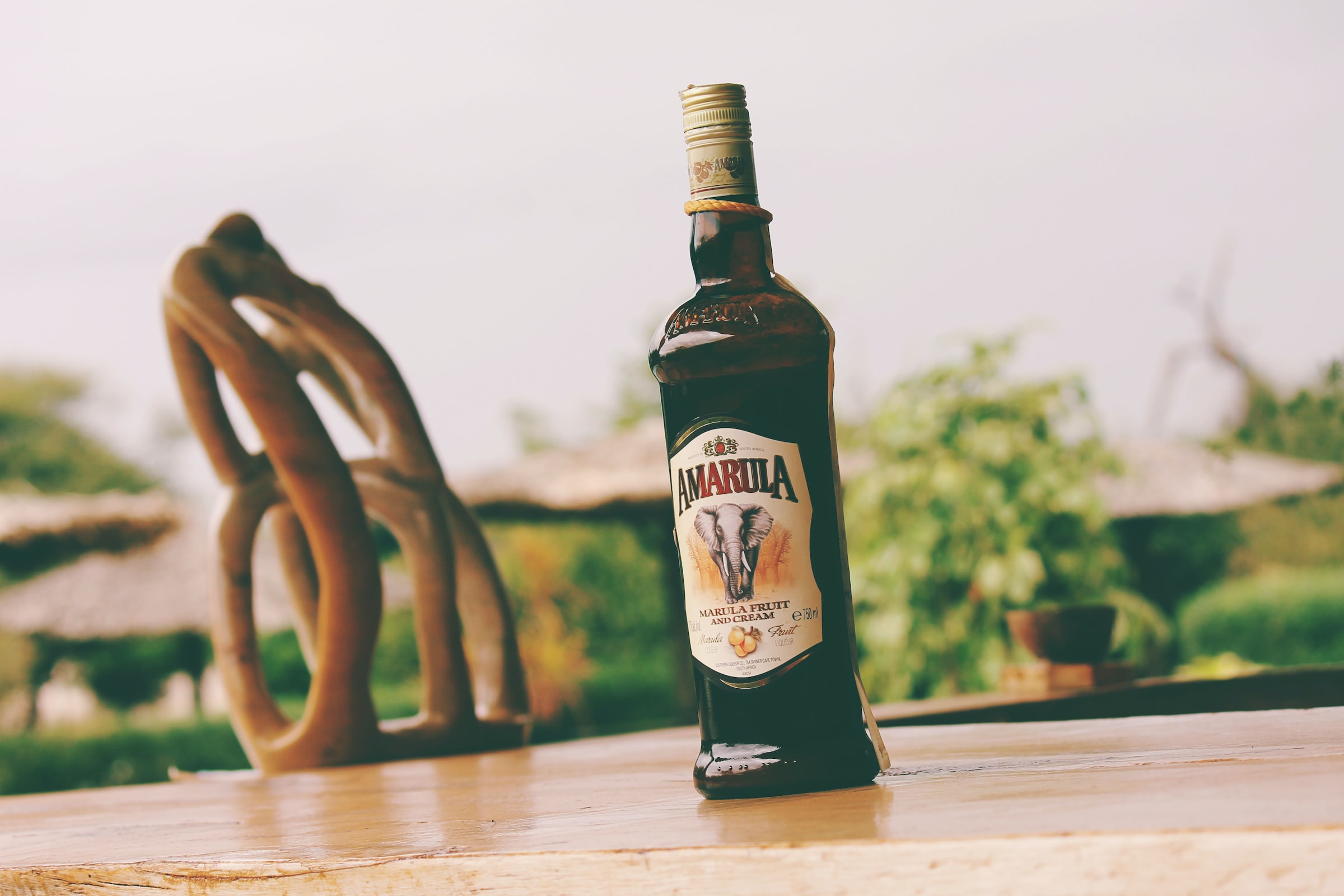 A bottle of Amarula sits outside on a wooden table