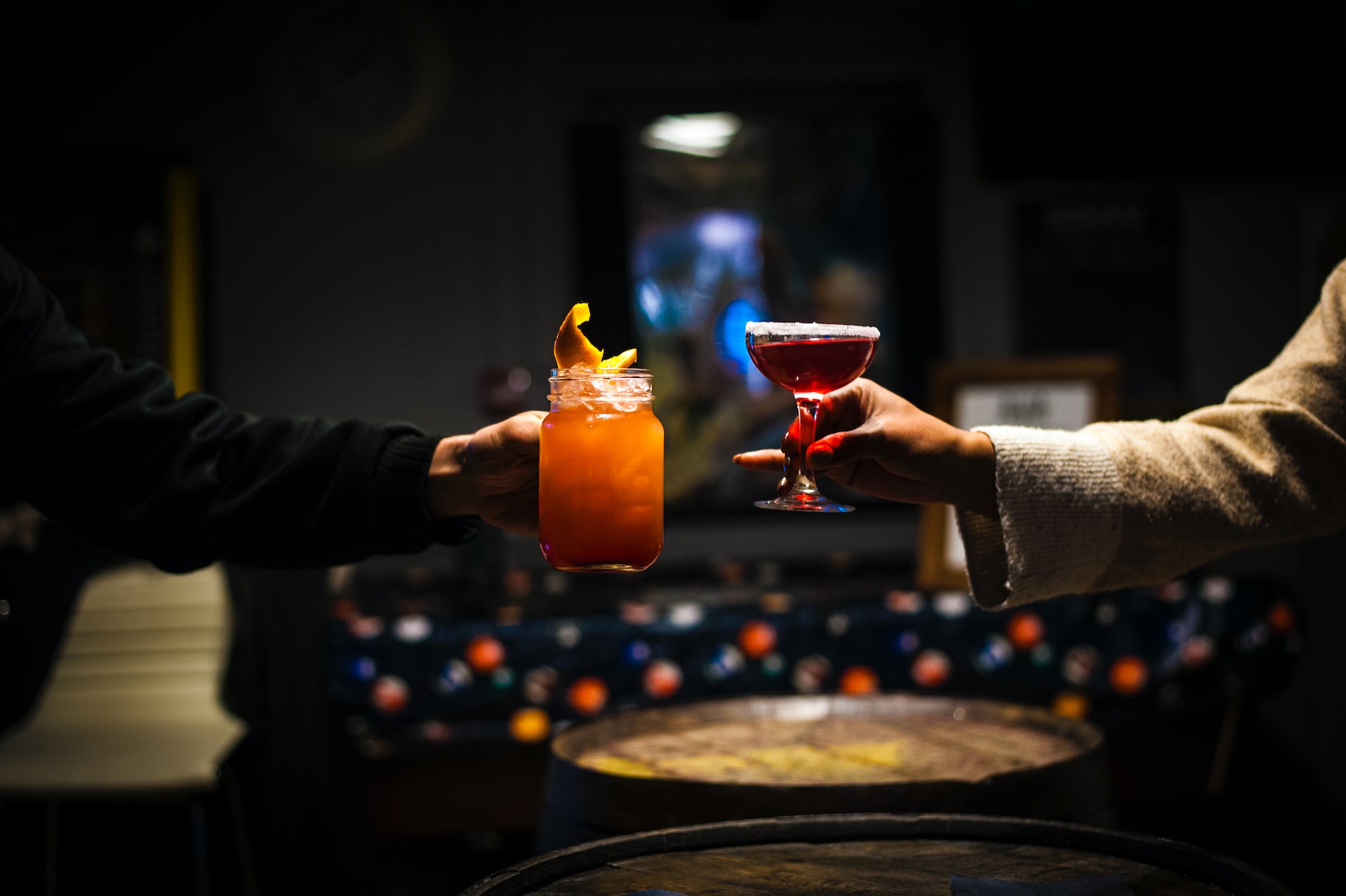Two people cheers a Southern Comfort spiked sweet tea in a mason jar and a Southern Comfort cranberry cocktail in a coup glass with a sugar rim.