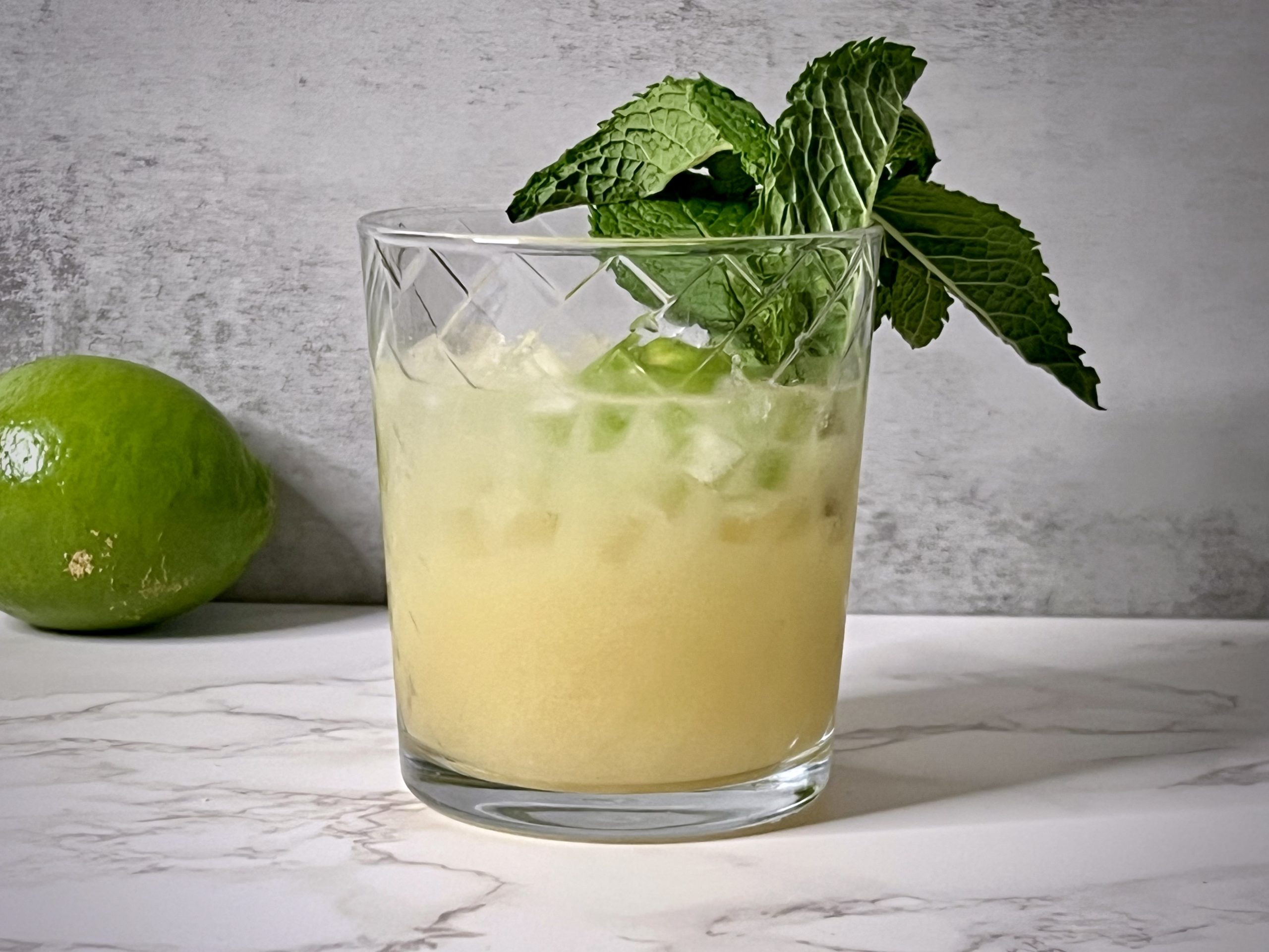 Close up of a Mai Tai with a lime in the background.