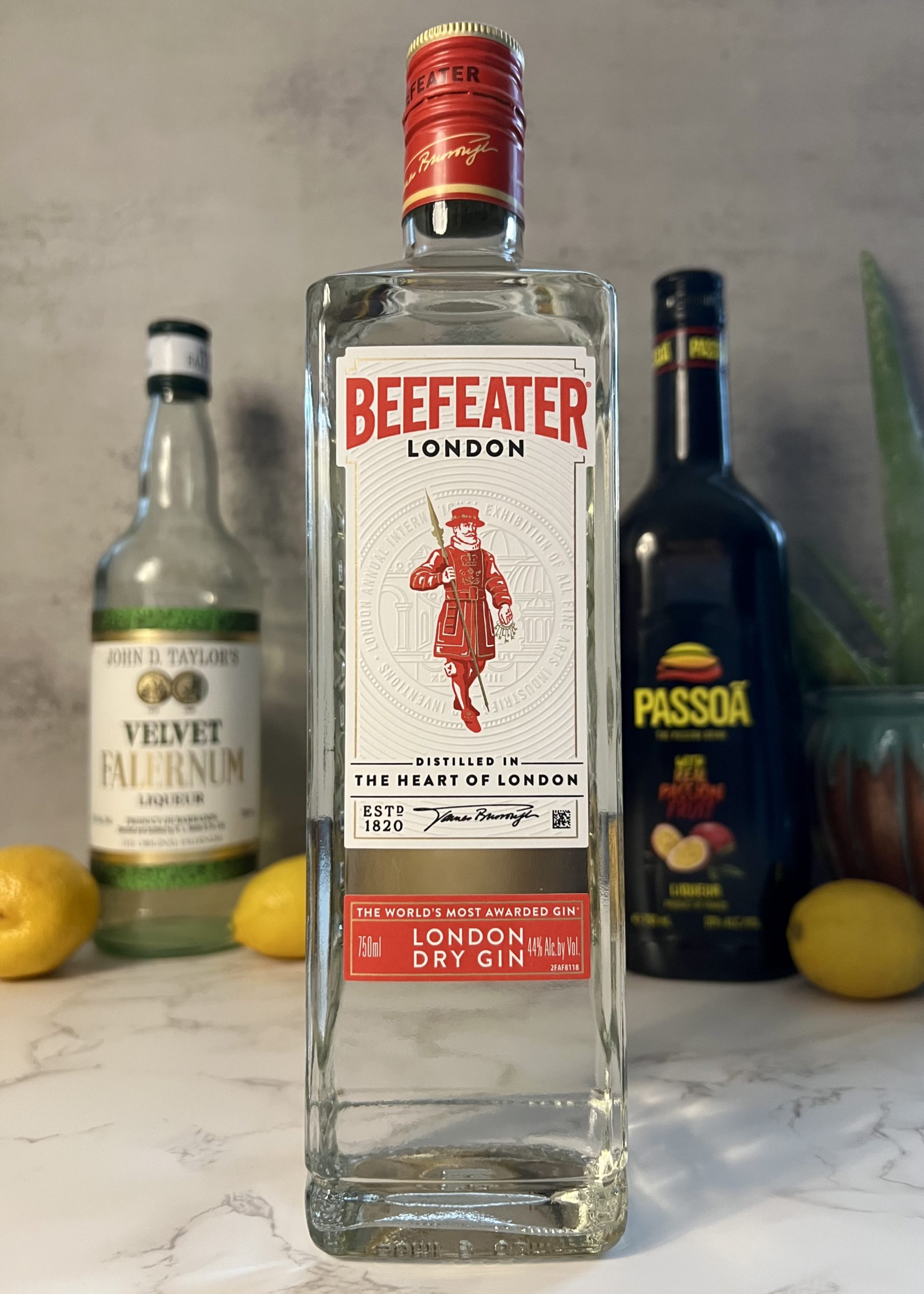 A closeup shot of a bottle of Beefeater Gin with other bottles and lemons blurred in the background.