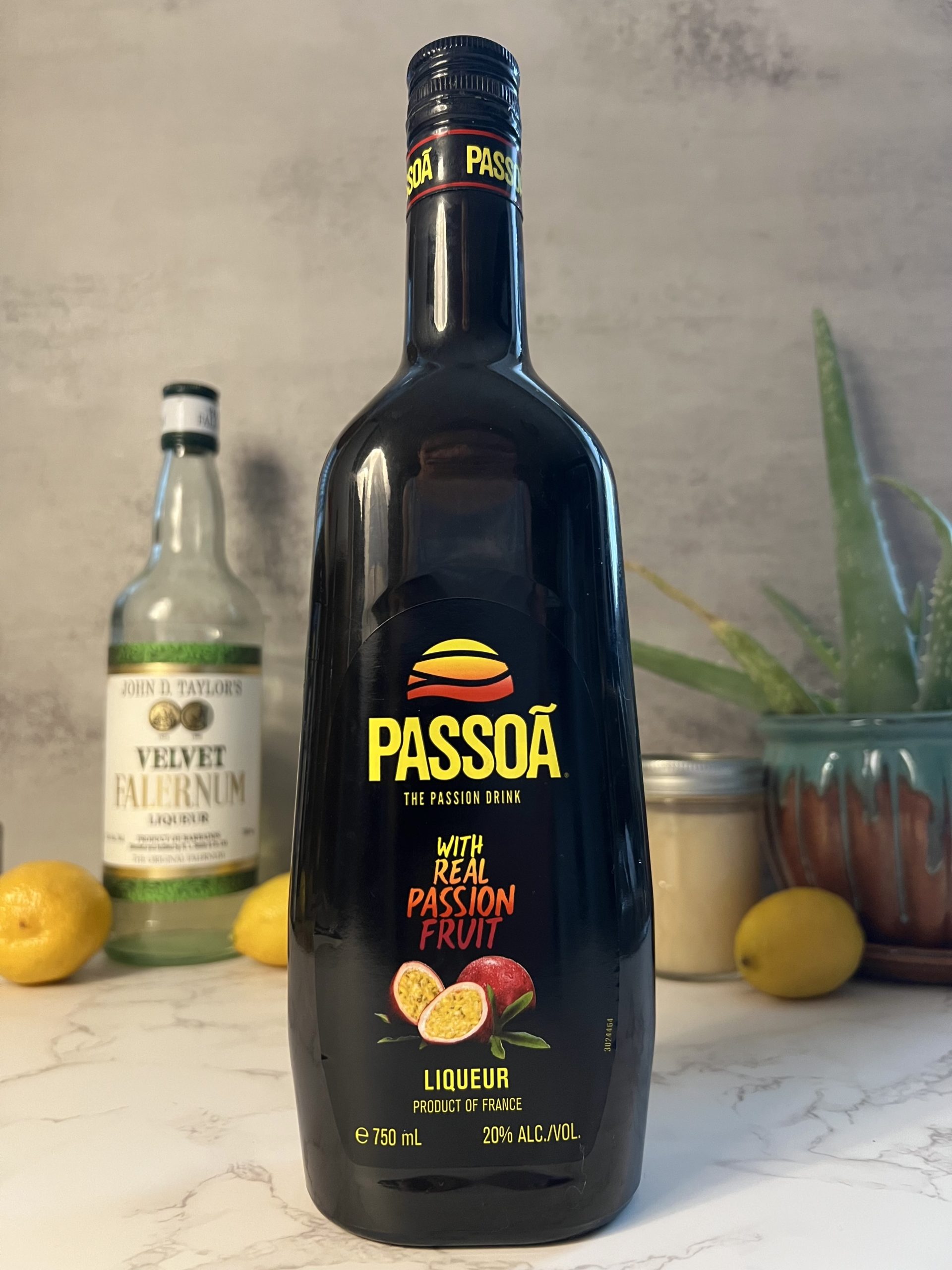 A closeup shot of a bottle of Passoa Passion Fruit Liqueur with other ingredients blurred out in the background.