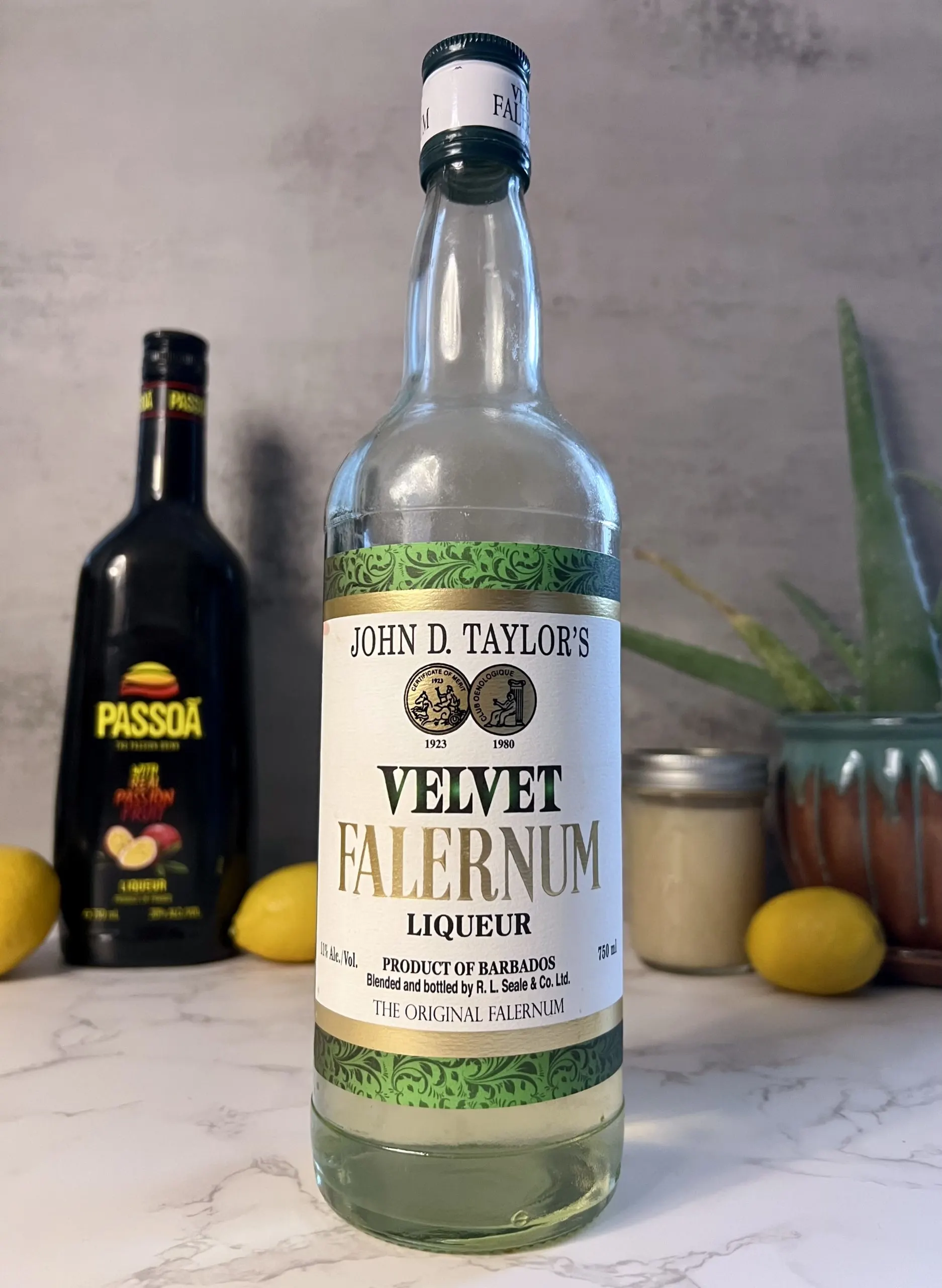 A closeup shot of a bottle of Velvet Falernum with other ingredients blurred out in the background.