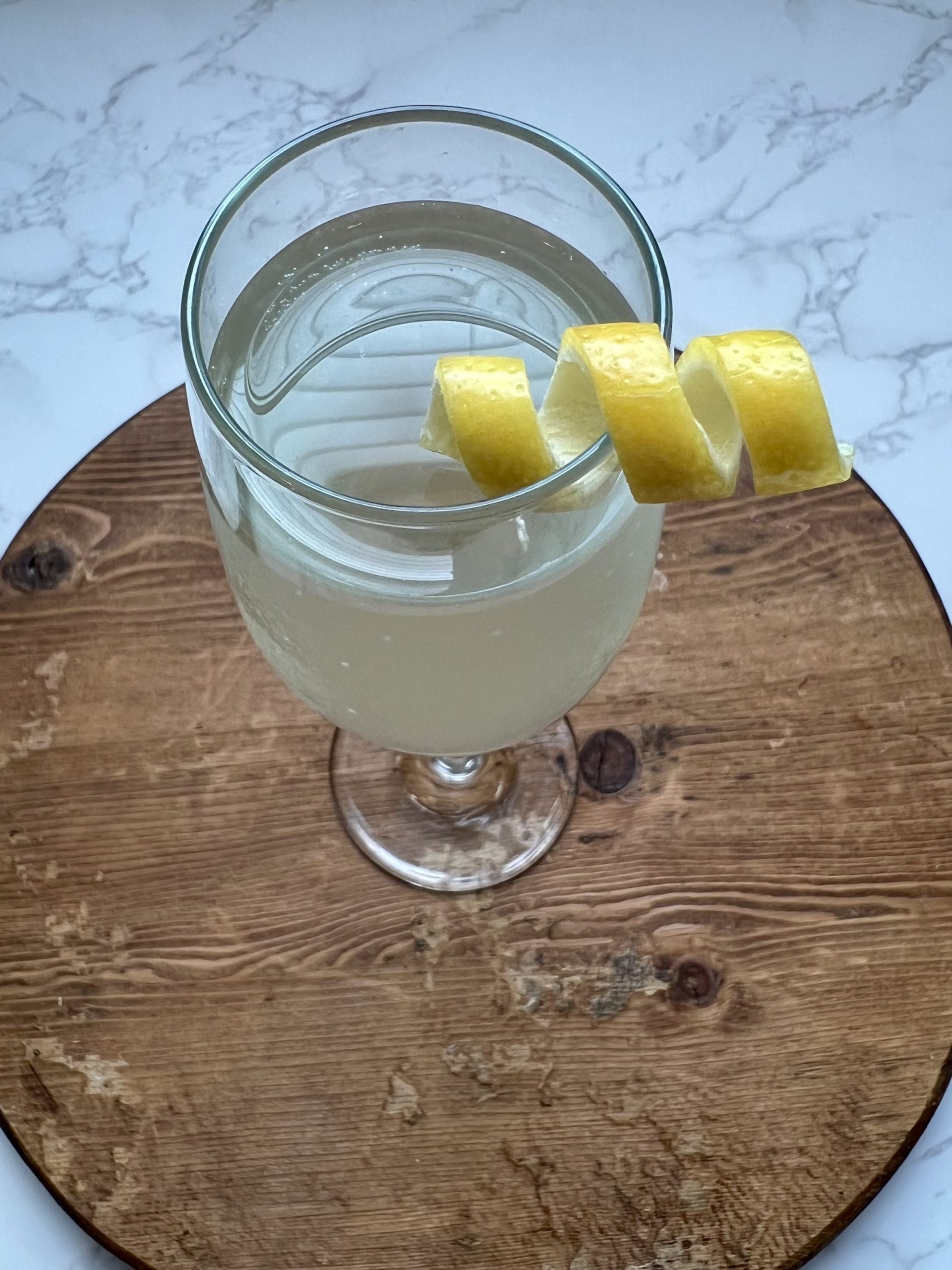 A close up of a lemon twist garnish on a glass of sparkling wine.